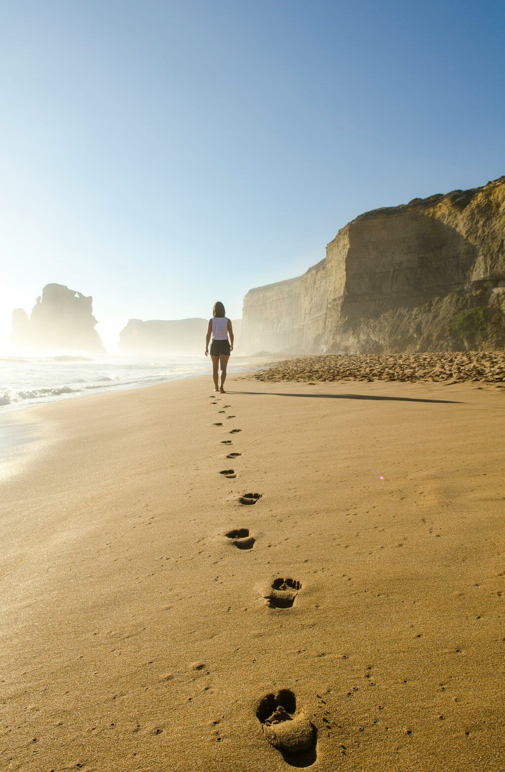 Person walking on the beach near some cliffs, Image by Brian Mann